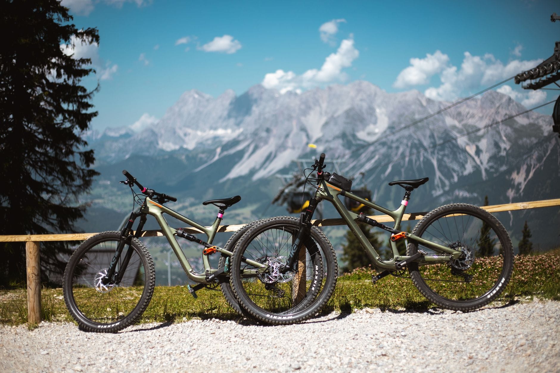 Dwa podejścia do roweru na maraton: ultralekki hardtail XC czy komfortowy downcountry full z rozsądnym skokiem Dwa rowery górskie przy drewnianym płocie na tle Alp austrianich