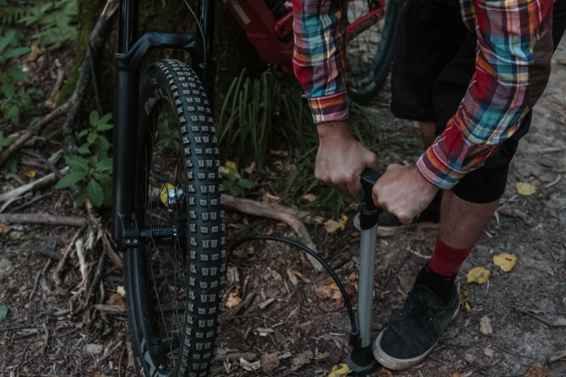 Kolarz pompuje oponę roweru enduro w lesie podczas serwisu