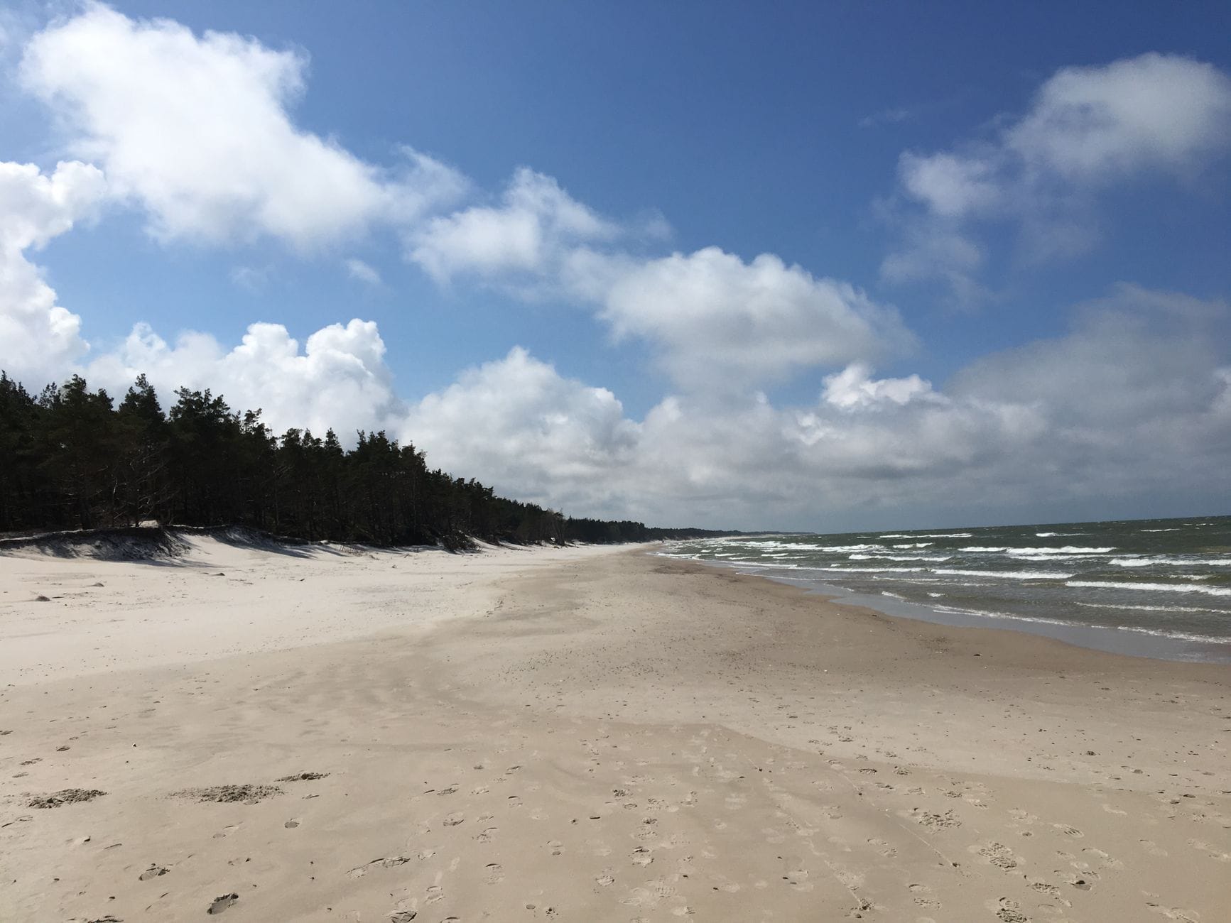 Spokojna plaża w Łebie z delikatnymi falami i jasnym, bezchmurnym niebem