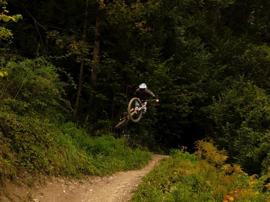 Rowerzysta górski w locie nad leśną trasą MTB