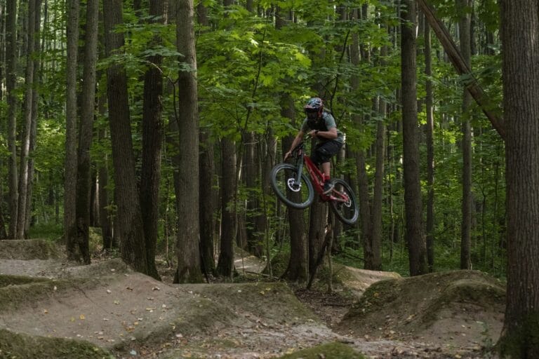 Rowerzysta wykonujący skok BMX na leśnej trasie