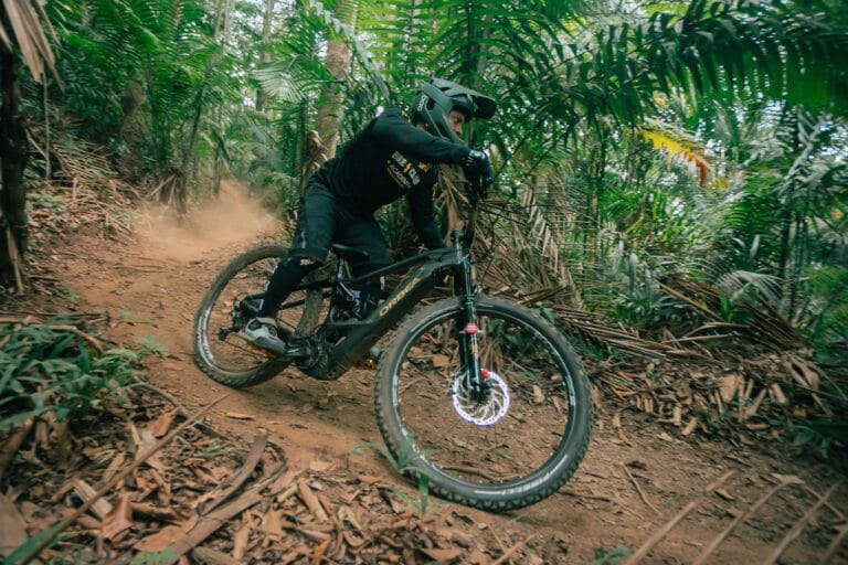Rowerzysta górski wykonujący manewr na leśnej trasie enduro