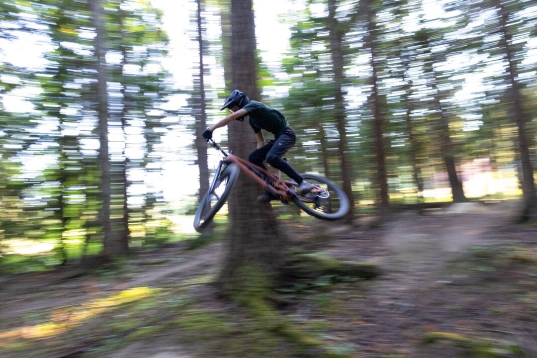 Rowerzysta górski wykonujący szybki skok na leśnej trasie enduro