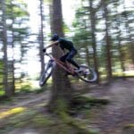 Rowerzysta górski wykonujący szybki skok na leśnej trasie enduro