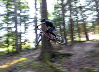 Moje doświadczenia z damperem sprężynowym w rowerze enduro: kiedy cewka wygrywa z powietrzem Rowerzysta górski wykonujący szybki skok na leśnej trasie enduro