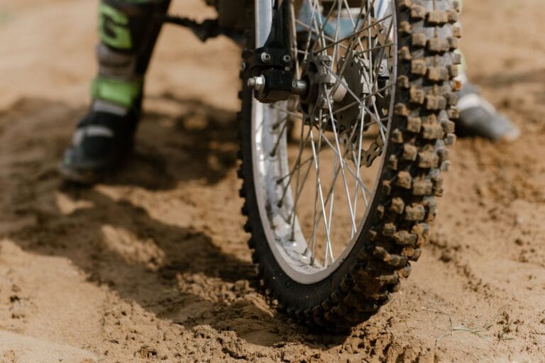 Zbliżenie na błotnistą oponę motocykla terenowego na piasku